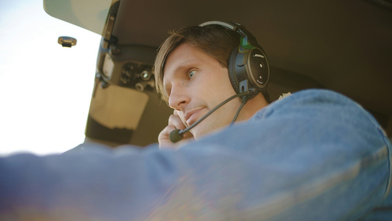 Pilot wearing a headset in a cockpit during flight operations.